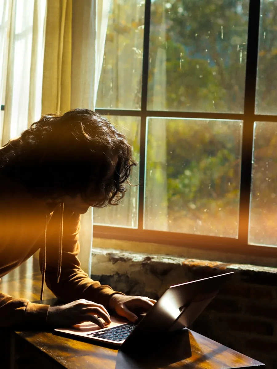 A traveler planning a trip on a laptop by a sunlit window